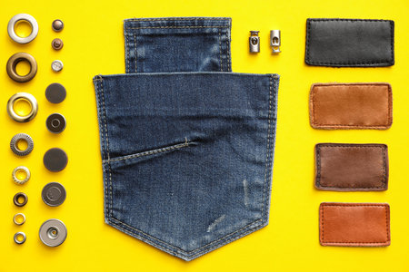 Flat lay composition with garment accessories and cutting details for jeans on yellow backgroundの写真素材