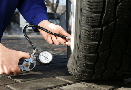 Mechanic checking tire air pressure at car service, closeupの写真素材