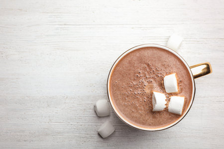 Cup of delicious hot cocoa with marshmallows on white wooden table, flat lay. Space for textの写真素材