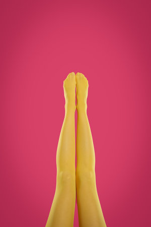 Woman wearing yellow tights on crimson background, closeup of legsの写真素材