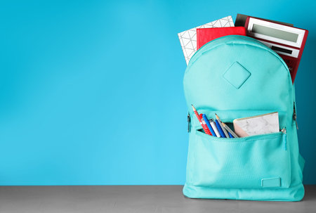 Stylish backpack with different school stationery on table against light blue background. Space for textの写真素材