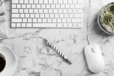 Flat lay composition with mouse and keyboard on white marble table