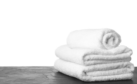 Folded fresh clean towels for bathroom on table against white background. Space for textの写真素材