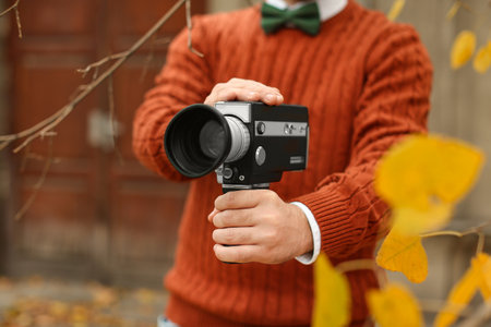 Young man with vintage video camera outdoors, closeupの写真素材