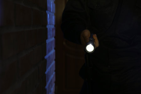 Male security guard with flashlight near brick wall in darknessの写真素材