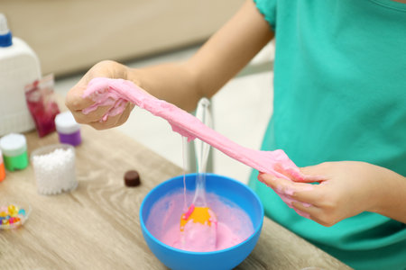 Little girl making DIY slime toy at table indoors, closeupの写真素材