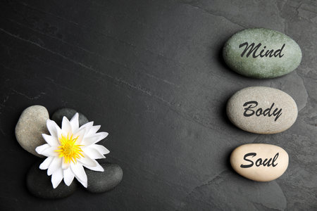 Lotus flower, stones with words Mind, Body, Soul and space for text on black background, flat lay. Zen lifestyleの写真素材