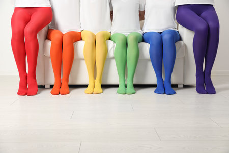 Women wearing colorful tights sitting on sofa indoors, closeupの写真素材