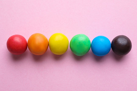 Colorful candies on pink background, flat lay. rainbow palette