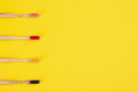 Toothbrushes made of bamboo on yellow background, flat lay. Space for text