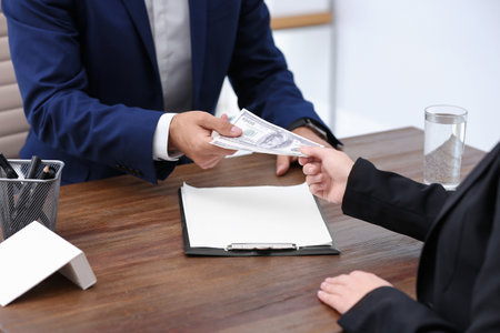 Woman giving bribe money to man at table, closeupの写真素材