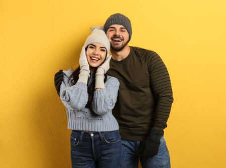 Happy young couple in warm clothes on yellow background. Winter vacationの写真素材