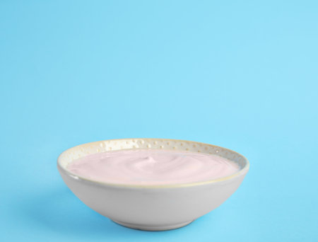 Tasty organic yogurt on light blue background. Space for textの写真素材