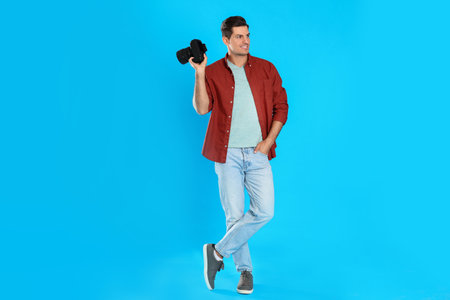 Professional photographer working on light blue background in studio