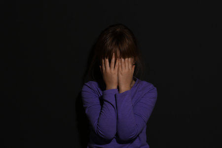 Abused little girl crying near black wall. domestic violence conceptの写真素材