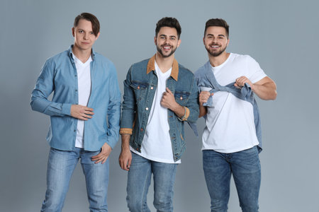 Group of young men in stylish jeans on grey backgroundの写真素材