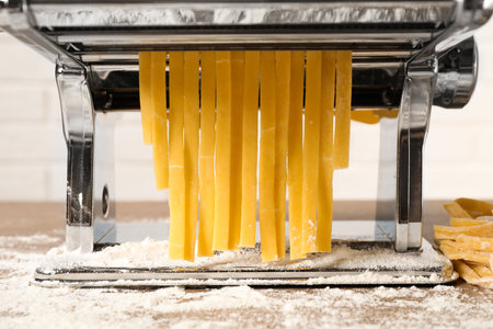 Pasta maker machine with dough on table, closeupの写真素材
