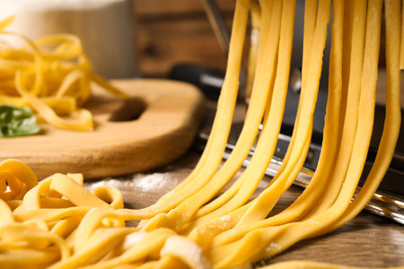 Pasta maker machine with dough on wooden table, closeupの写真素材