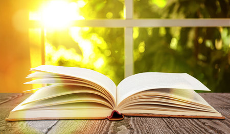 Open old hardcover book on wooden table indoorsの写真素材