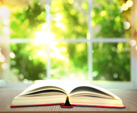 Open old hardcover book on wooden table indoorsの写真素材