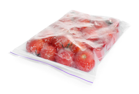 Frozen tomatoes in plastic bag isolated on white. vegetable preservationの写真素材