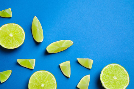 Juicy fresh lime slices on blue background, flat lay. Space for textの写真素材