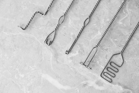 Set of different logopedic probes on marble table, flat lay. Speech therapist's tools