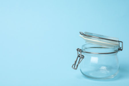 Open empty glass jar on light blue background, space for textの写真素材