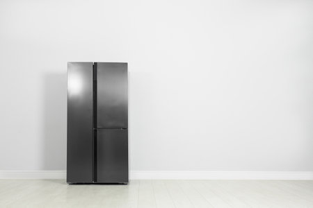 Modern refrigerator near light gray wall, space for textの写真素材
