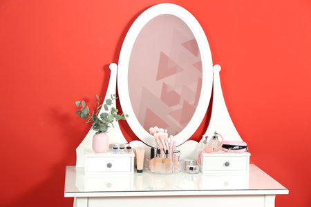 Dressing table with mirror and makeup products near red wallの写真素材