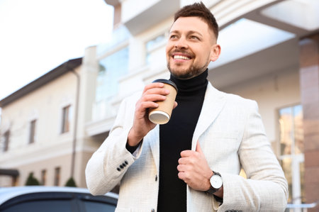 Businessman with cup of coffee on city street in the morningの写真素材