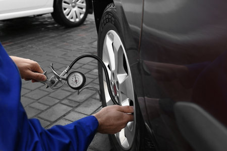 Mechanic checking tire air pressure at car service, closeupの写真素材