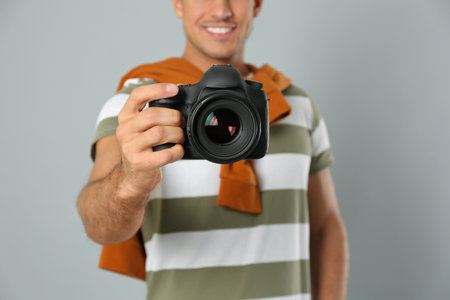 Professional photographer working on light gray background in studio, focus on camera
