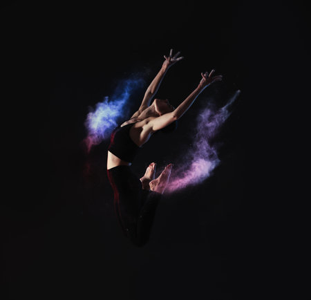 Professional acrobat with chalk powder exercising in dark studio