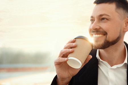 Man with cup of coffee on city street in the morningの写真素材