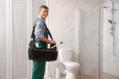 Professional plumber with toolbox near toilet bowl in bathroomの写真素材