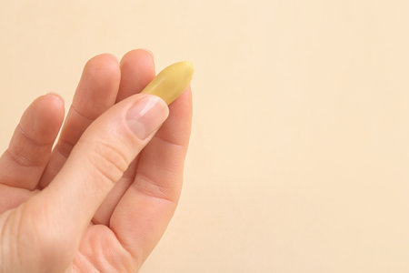 Closeup view of woman holding suppository on beige background, space for text. Hemorrhoid treatmentの写真素材