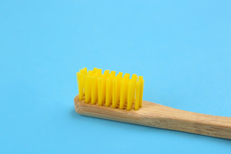 Toothbrush made of bamboo on light blue background, closeup