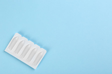 Suppositories and space for text on light blue background, top view. Hemorrhoid treatment