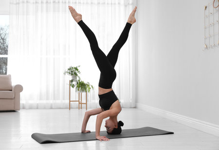 Professional young acrobat practicing yoga at home