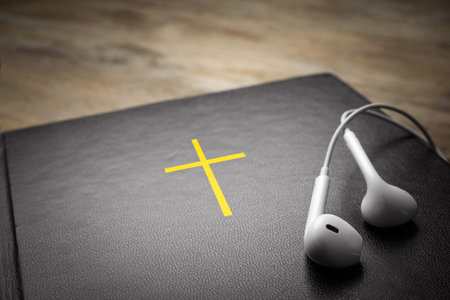 Bible and earphones on table, closeup. religious audiobook
