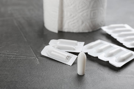 Suppositories on gray stone table. Hemorrhoid treatment