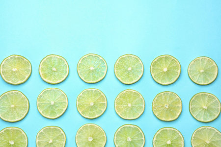 Fresh juicy lime slices on light blue background, flat lay. Space for textの写真素材