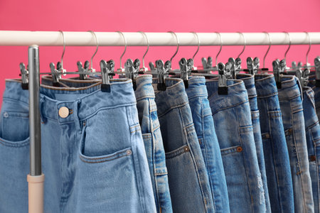 Rack with stylish jeans on pink background, closeupの写真素材