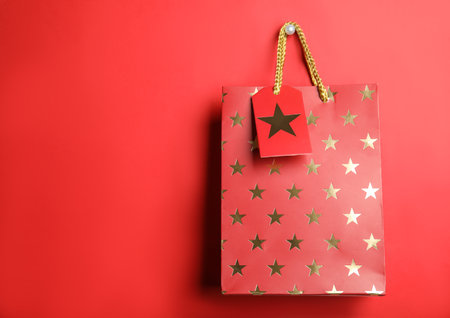 Shopping paper bag with star pattern on red background, space for textの写真素材