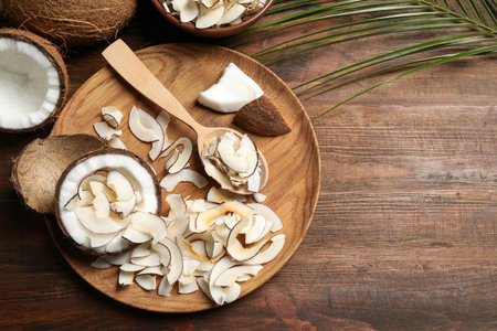 Flat lay composition with tasty coconut chips on wooden table