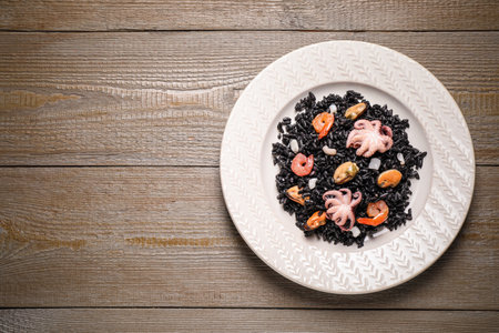 Delicious black risotto with seafood on wooden table, top view. Space for textの写真素材