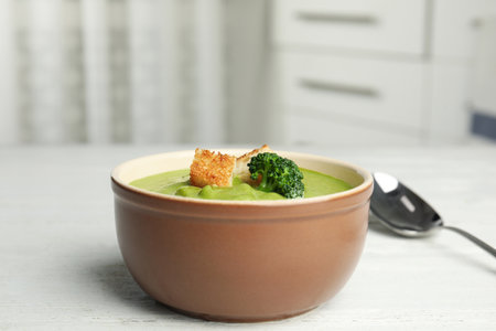 Delicious broccoli cream soup with croutons served on white wooden table indoorsの写真素材