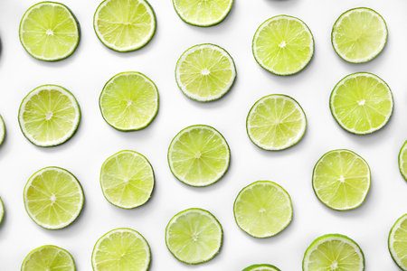 Slices of fresh juicy limes on white background, flat layの写真素材