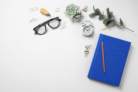 Glasses, alarm clock, eucalyptus and different stationery on white background, top view. Classic blue - color of the Year 2020の写真素材